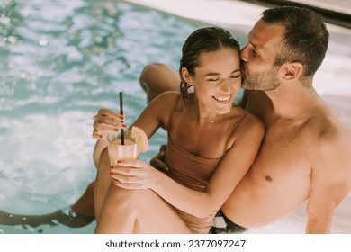 Handsome young couple relaxing by the indoor swimming pool - Powered by Shutterstock