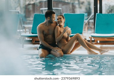 Handsome young couple relaxing by the indoor swimming pool - Powered by Shutterstock