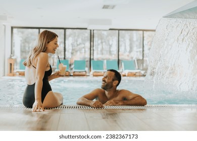 Handsome young couple relaxing by the indoor swimming pool - Powered by Shutterstock