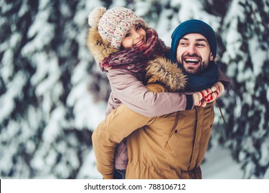 Handsome Young Dad And His Little Cute Daughter Are Having Fun Outdoor In Winter. Enjoying Spending Time Together. Family Concept.