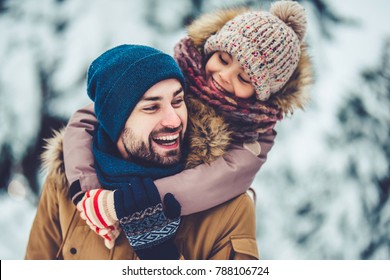 Handsome Young Dad And His Little Cute Daughter Are Having Fun Outdoor In Winter. Enjoying Spending Time Together. Family Concept.