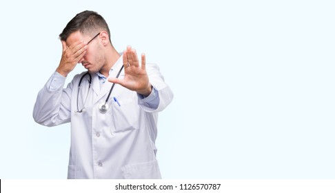 Handsome Young Doctor Man Covering Eyes With Hands And Doing Stop Gesture With Sad And Fear Expression. Embarrassed And Negative Concept.