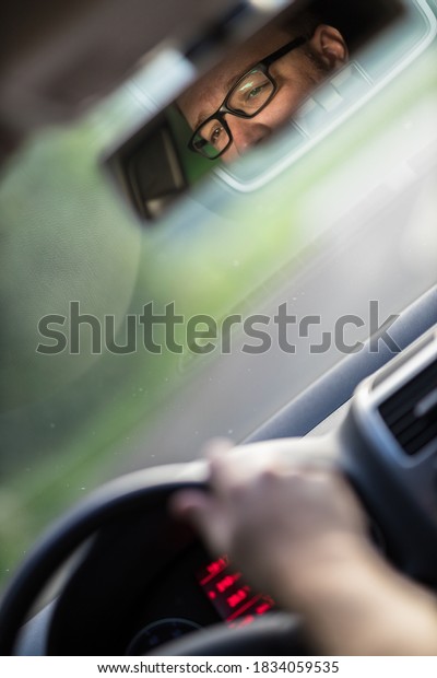 Handsome young driver driving hic car fast yet\
safely on the road