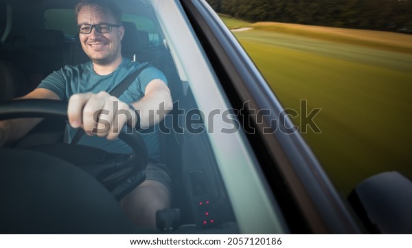 Handsome young driver driving hic car fast\
yet safely on the road (motion blurred\
image)
