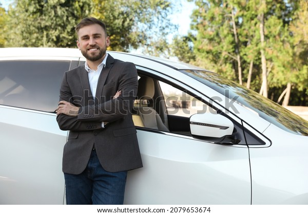 Handsome\
young driver near modern car on city\
street
