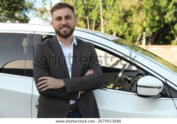 Handsome\
young driver near modern car on city\
street