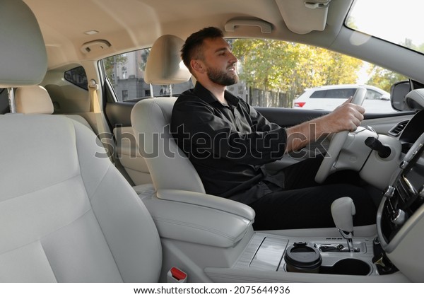 Handsome young driver\
sitting in modern car