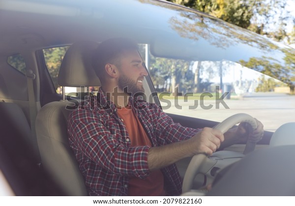 Handsome young driver sitting in modern car,\
view through\
windshield