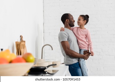 handsome young father holding his daughter at kitchen