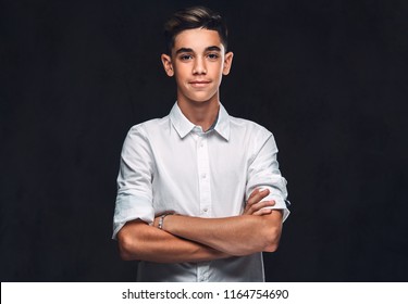 Handsome young guy dressed in white shirt standing with crossed arms. Isolated on the dark background.