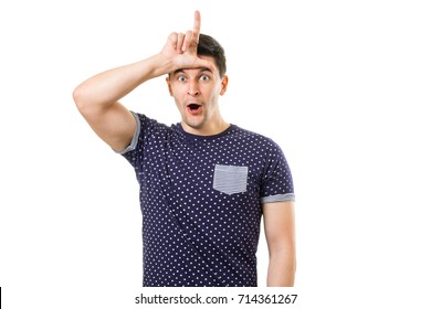 Handsome young guy with funny expression on face showing loser gesture by hand