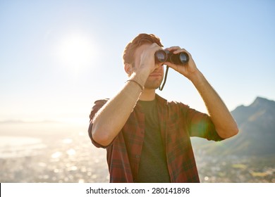 Handsome Young Guy Looking Through His Binoculars At The Horizon With Bright Sun Flare 