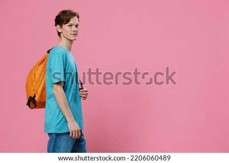 a handsome, young guy stands with a backpack on his back on a pink background with space for an advertising layout