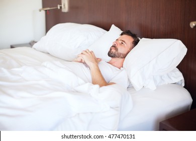 Handsome Young Hispanic Man Lying On His Bed With His Eyes Open Unable To Sleep