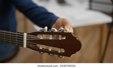 Handsome young hispanic man passionately tuning his classical guitar, setting the stage for a melodic performance in the heart of a cozy music studio - Powered by Shutterstock