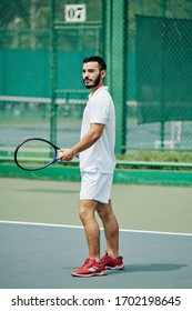 Handsome Young Hispanic Man In White Sports Clothing Playing Tennis Outdoors