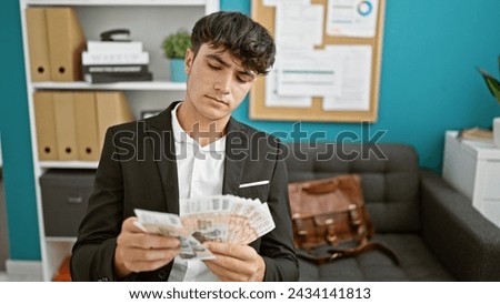 Handsome young hispanic teenager making business banknotes count â€“ working a serious, focused job indoors, surrounded by icelandic krona in a relaxed office.