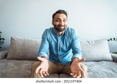 Handsome Young Indian Man Talking To Camera Feeling Clueless And Confused Gesturing With Arms And Hands. Millennial Eastern Student Or Videoconference Meeting Participant. Webcam View