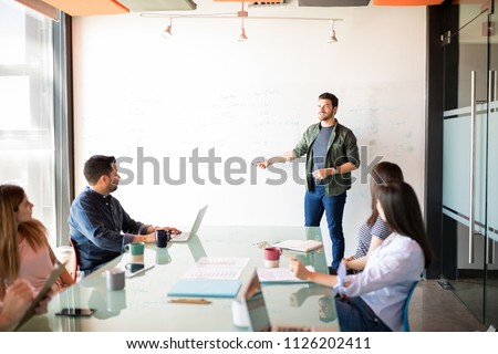 Handsome young latin businessman giving a presentation to a group of people in a meeting room