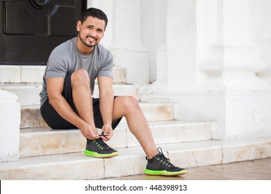 Handsome Young Latin Man Tying His Shoes And Getting Ready To Workout And Go For A Run Outdoors In The City