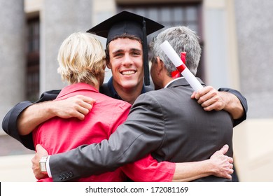 handsome young male graduate hugging his parents at graduation