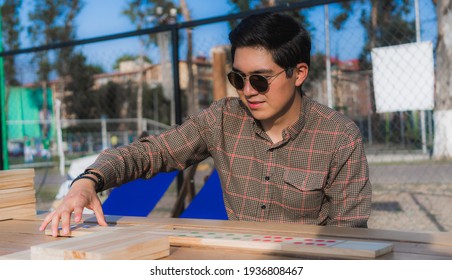 Handsome Young Man Arranging Giant Domino On A Wooden Table