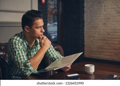 Handsome young man in a barbershop is waiting for the master in the waiting room while drinking coffee - Powered by Shutterstock