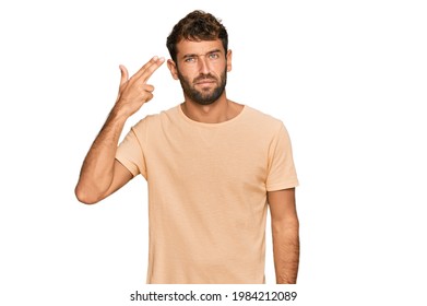 Handsome Young Man With Beard Wearing Casual Tshirt Shooting And Killing Oneself Pointing Hand And Fingers To Head Like Gun, Suicide Gesture. 