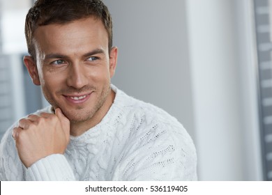Handsome Young Man With Beautiful Face, Smooth Soft Facial Skin And Stubble Beard. Portrait Attractive Male Model In White Sweater Indoors. Beauty, Skin Care And Man's Health Concepts. High Resolution