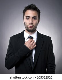 Handsome young man in black suit tightens his tie