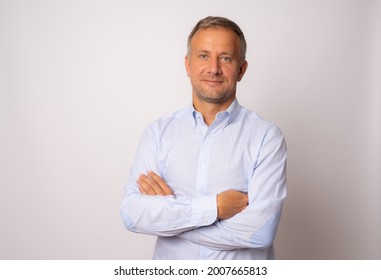 Handsome young man in blue shirt with arms crossed on white background