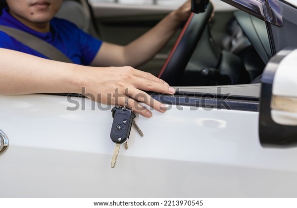 A handsome young man in a blue\
t-shirt in a hat holding his new car keys and smiling. Asian man\
with car keys in hand . The idea of ​​having a new\
car.