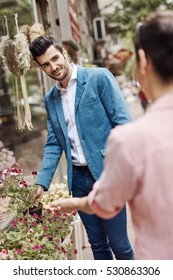 Handsome Young Man Buying Flowers At Florist, Smiling.