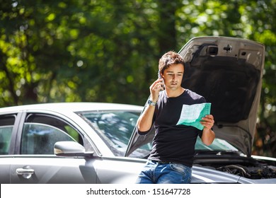 Handsome young man calling for assistance with his car broken down by the roadside