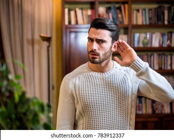 Handsome Young Man Can't Hear, Putting Hand Around His Ear. Indoors Shot Inside A House