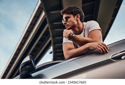 Handsome Young Man In Casual Clothes Standing Near His Modern Sport Car On The Street