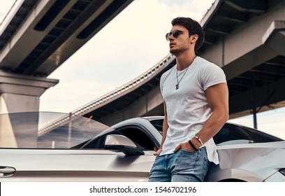 Handsome Young Man In Casual Clothes Standing Near His Modern Sport Car On The Street