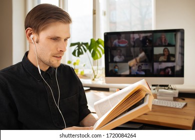 Handsome Young Man In Casual Clothes Reading A Book In A Video Conference Call  Group Video Chat Book Club Online While Practicing Social Distancing. Online Education In Video Conferencing App 