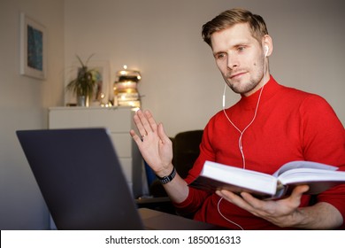 Handsome Young Man In Casual Red Clothes Reading A Book In A Video Conference Call. Book Club Online  Social Distancing. Online Education In Video Conferencing. Virtual Bible Study. Book Circle