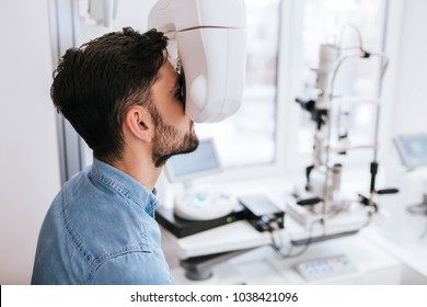 Handsome young man is checking the eye vision in modern ophthalmology clinic. Patient in ophthalmology clinic
