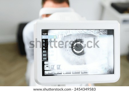 Handsome young man is checking the eye vision in modern ophthalmology clinic. Patient in ophthalmology clinic.