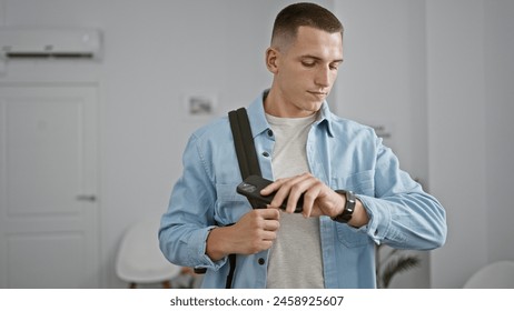 Handsome young man checking smartwatch in a bright modern indoor setting - Powered by Shutterstock