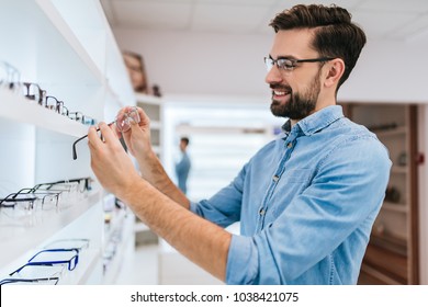 Handsome young man is choosing the most appropriate eyeglasses in modern ophthalmology clinic. - Powered by Shutterstock