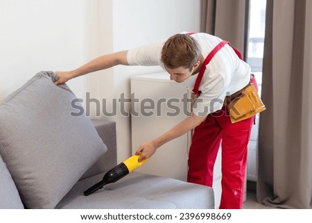 Handsome young man cleaning furniture. Process of deep furniture cleaning, removing dirt from sofa. Washing concept