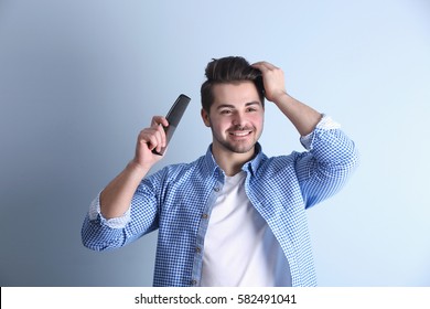 Handsome Young Man Combing Hair On Color Background