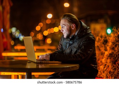handsome young man with a computer on the street at night - Shutterstock ID 580675786