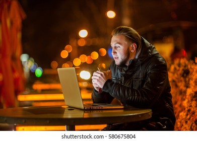 handsome young man with a computer on the street at night - Shutterstock ID 580675804