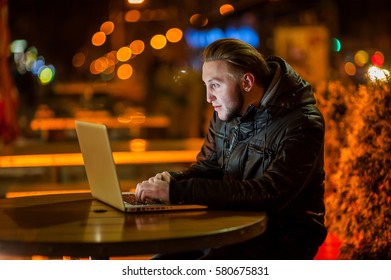 handsome young man with a computer on the street at night - Shutterstock ID 580675831