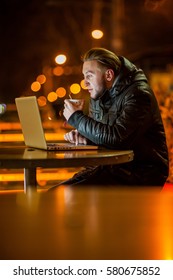 handsome young man with a computer on the street at night - Shutterstock ID 580675852