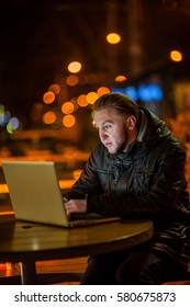 handsome young man with a computer on the street at night - Shutterstock ID 580675873